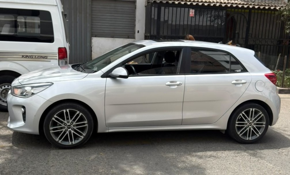 Kia hatchback plateado estacionado en la calle sin cobertor